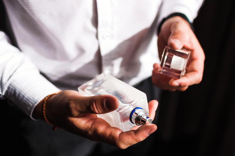 Man holding bottle of perfume and smells fragrance
