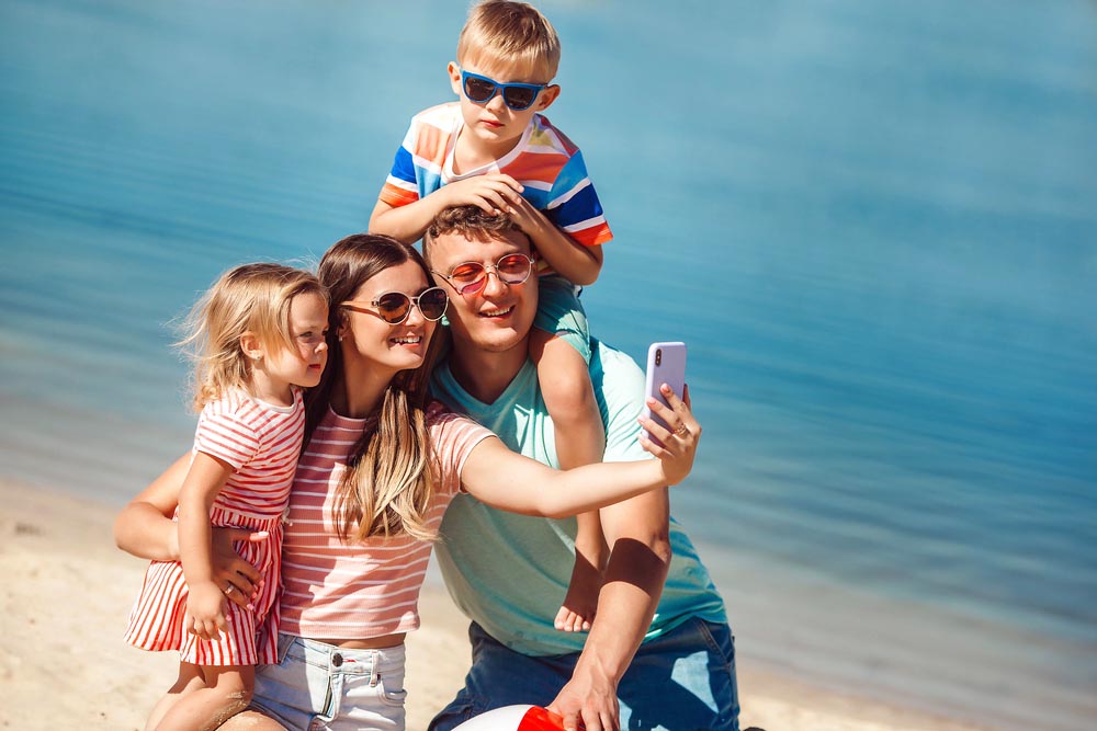 Happy family on the beach. Family vacation. People making selfie on cell phone