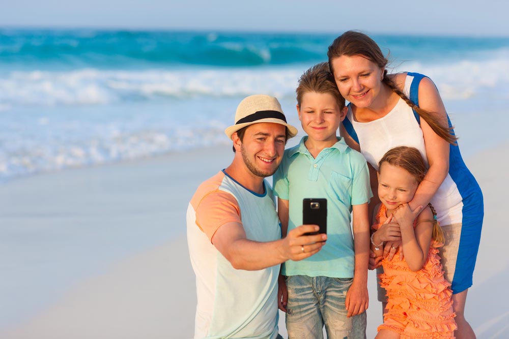 Beautiful family at beach making a self portrait with a mobile phone